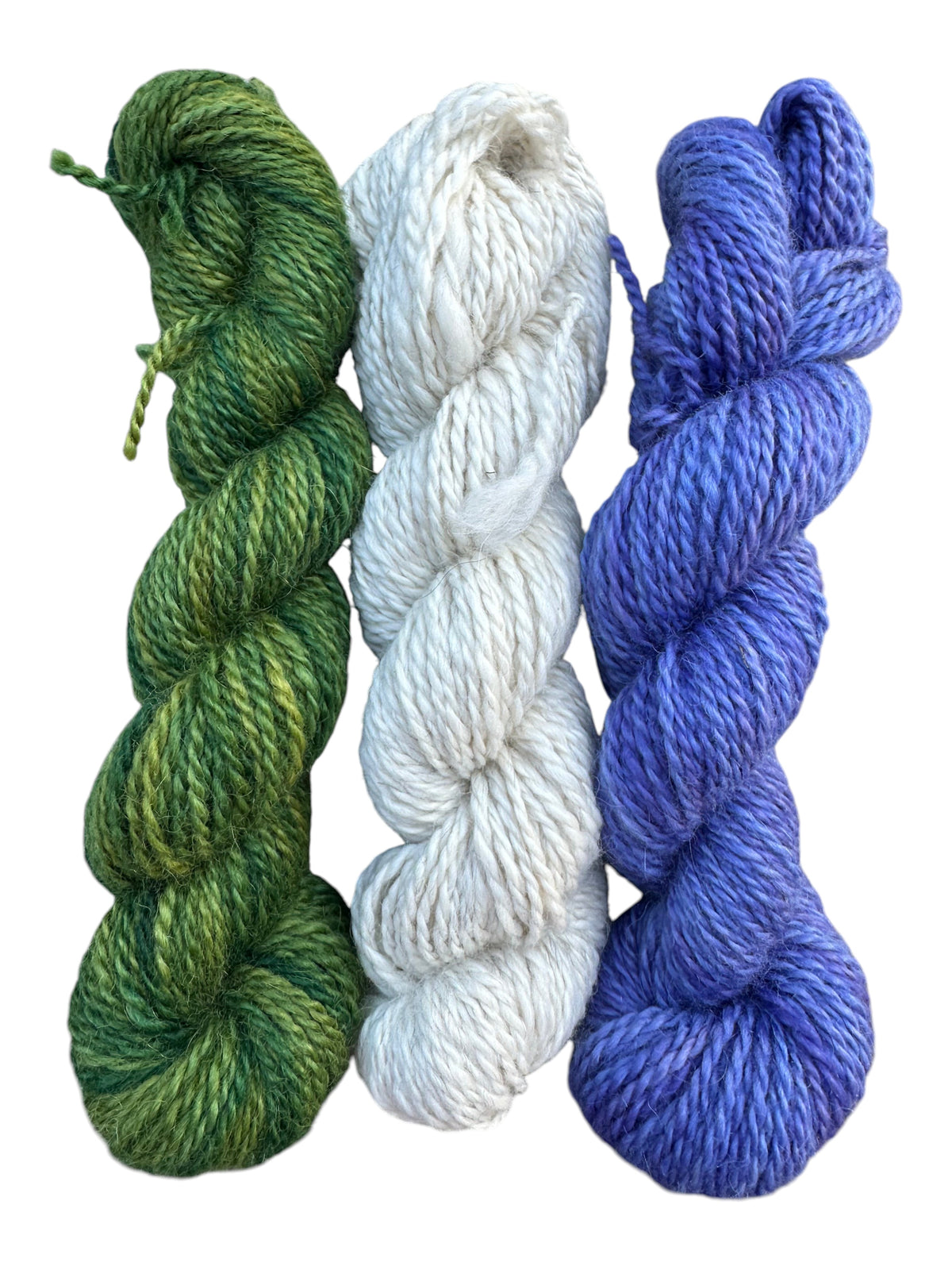 Oak Crest Alpacas and More three skeins of worsted weight alpaca yarn in green, cream, and periwinkle blue.