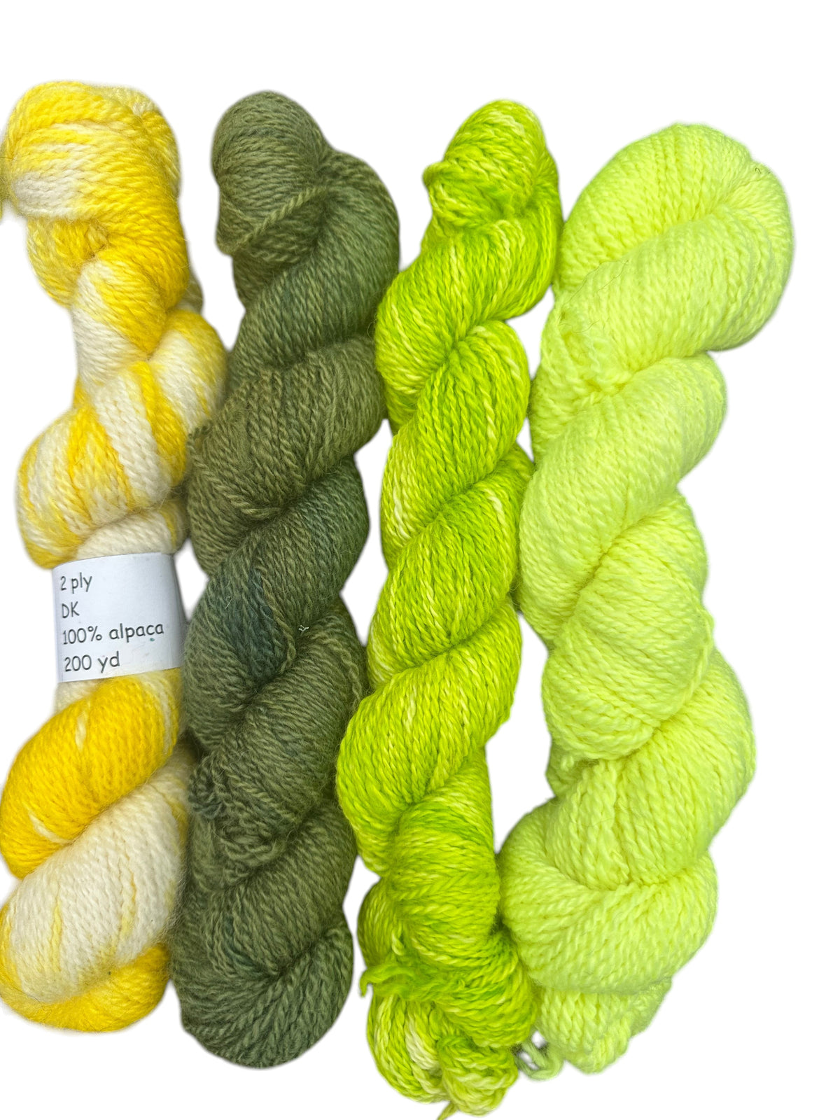 Oak Crest Alpacas and More hand-dyed 100% alpaca DK yarn skeins in shades of yellow, olive green, and lime green.