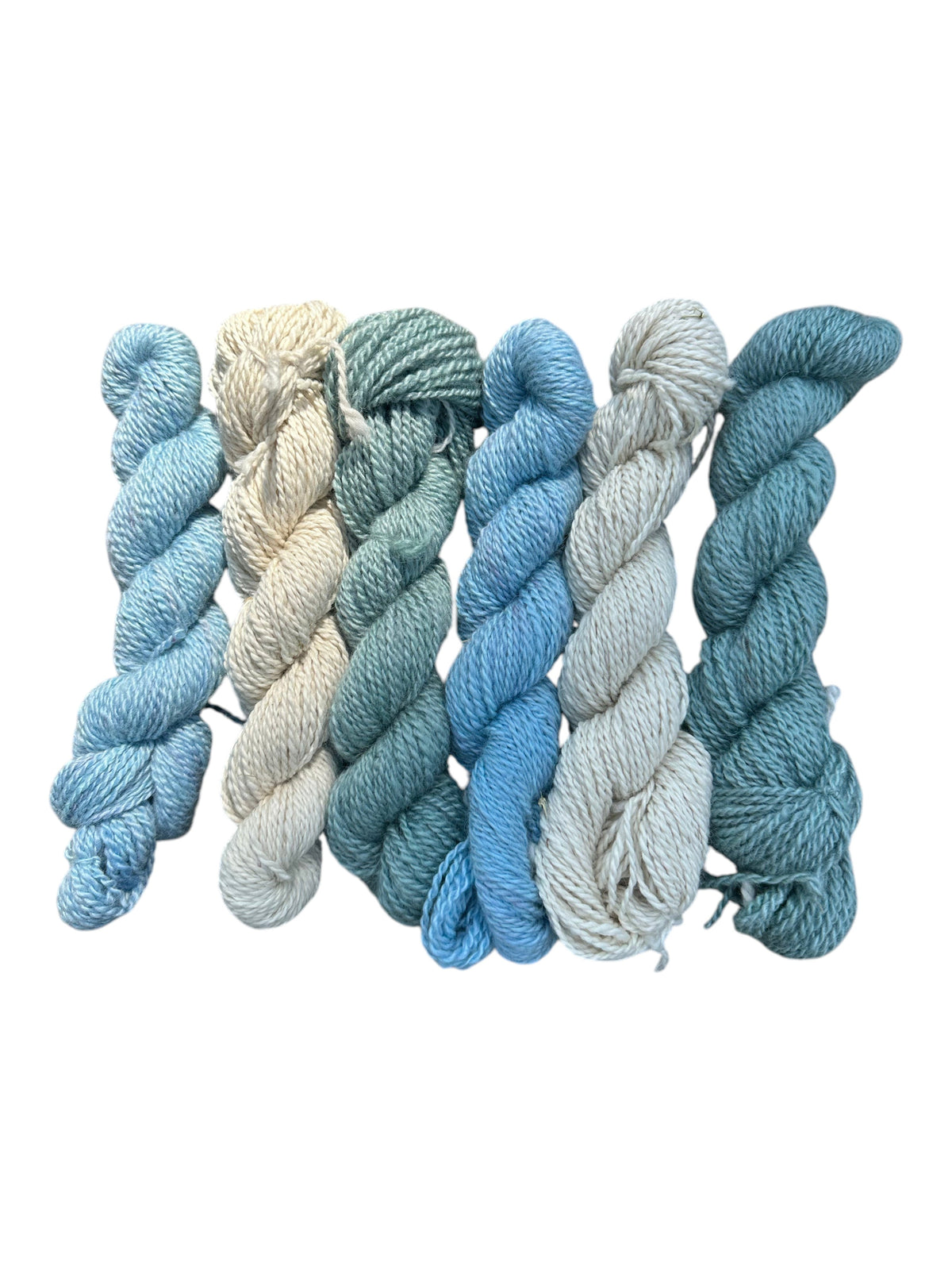 Oak Crest Alpacas and More worsted weight alpaca yarn skeins in blue, green, and natural cream colorways