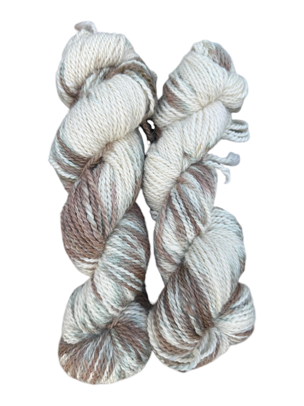 Two skeins of Oak Crest Alpacas and More hand-dyed variegated worsted alpaca yarn in cream, brown, and grey tones.