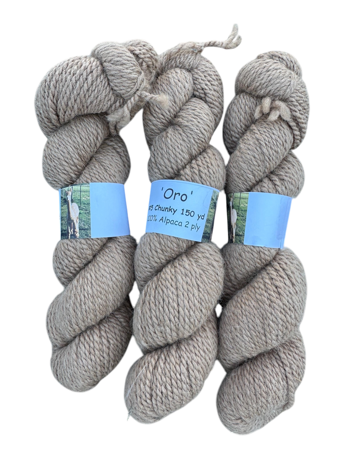 Three skeins of Oak Crest Alpacas and More chunky 2-ply natural fawn alpaca yarn labeled Oro on a white background.