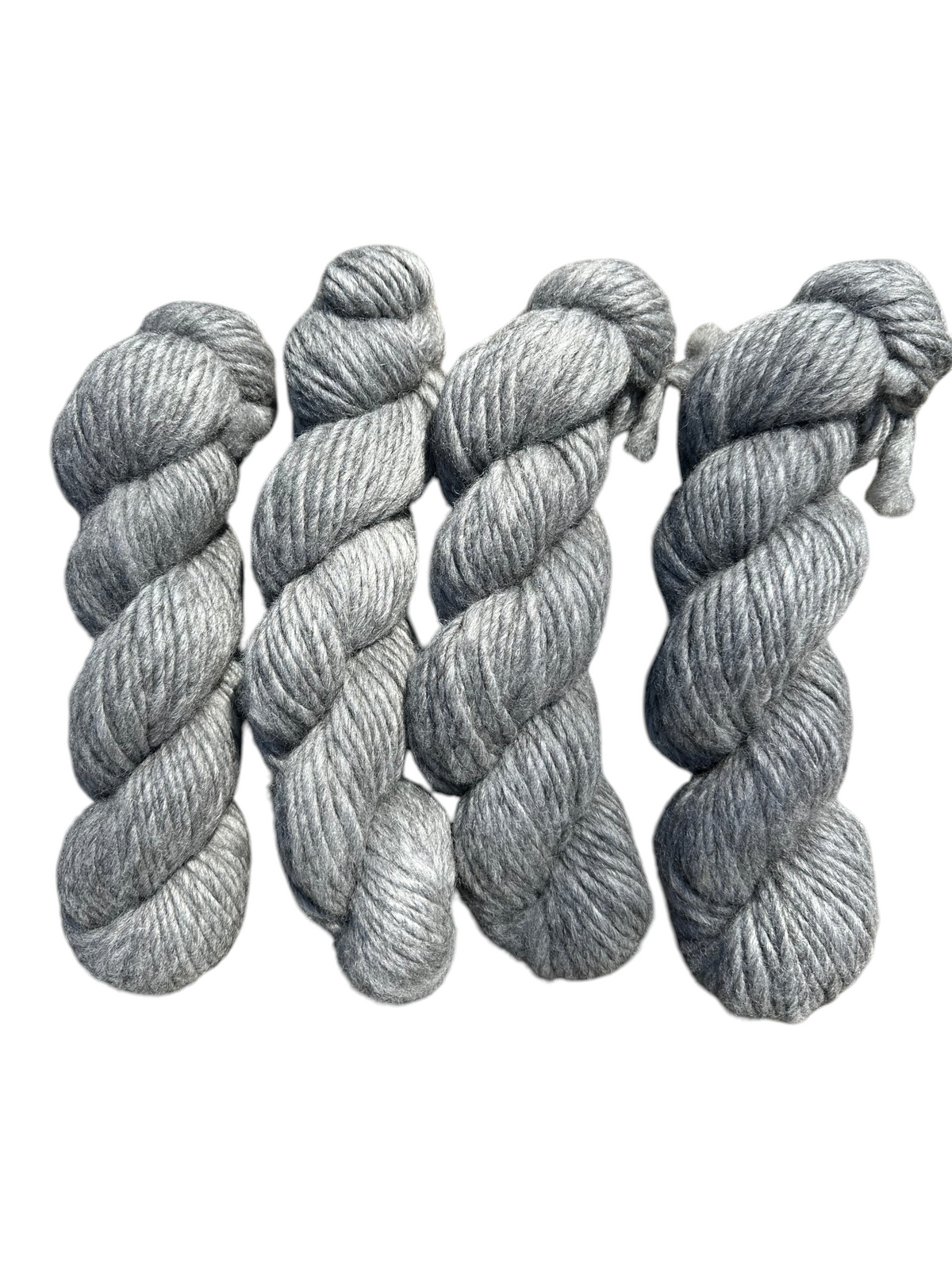 Four skeins of gray Oak Crest Alpacas and More super bulky 1-ply alpaca yarn with a rustic low-twist texture.