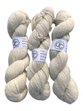 Three skeins of Oak Crest Alpacas and More natural cream worsted 100% alpaca yarn with 2-ply texture.