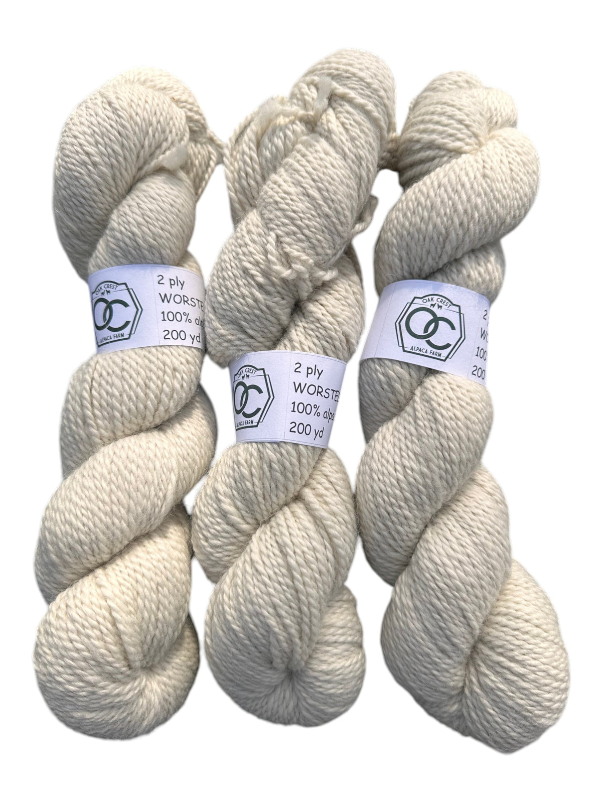 Three skeins of Oak Crest Alpacas and More natural cream worsted 100% alpaca yarn with 2-ply texture.