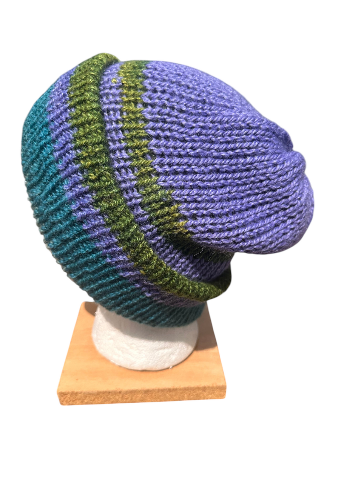 Oak Crest Alpacas and More reversible double knit alpaca hat in purple, teal, and green stripes on a display head.