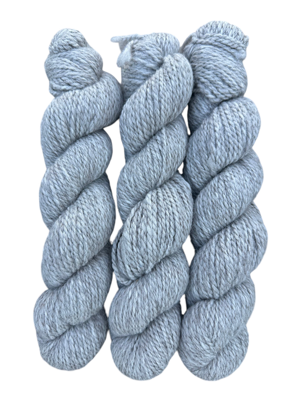 Three skeins of Oak Crest Alpacas and More chunky 2-ply silver gray alpaca yarn in a soft natural undyed fiber