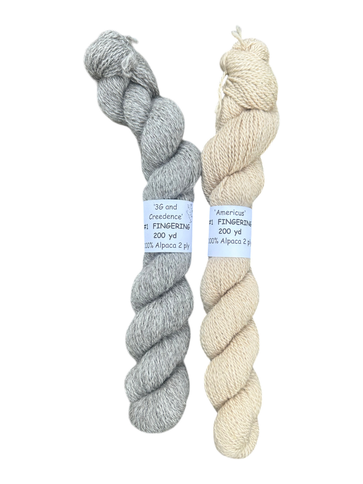 Two skeins of Oak Crest Alpacas and More fingering weight yarn in medium silver gray and light fawn natural colors.