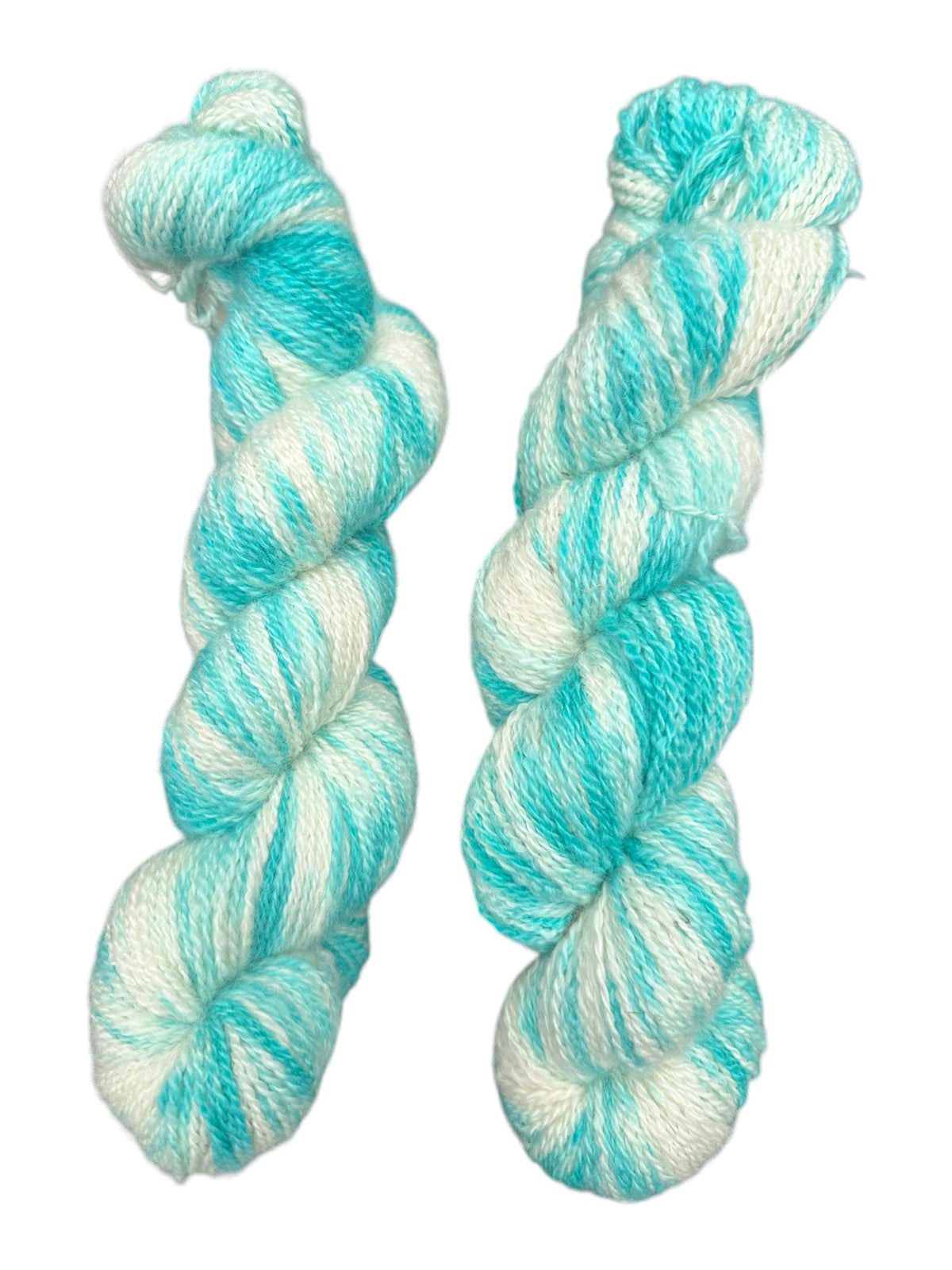 Two skeins of Oak Crest Alpacas and More hand-dyed fingering weight alpaca yarn in white and turquoise variegated hues.