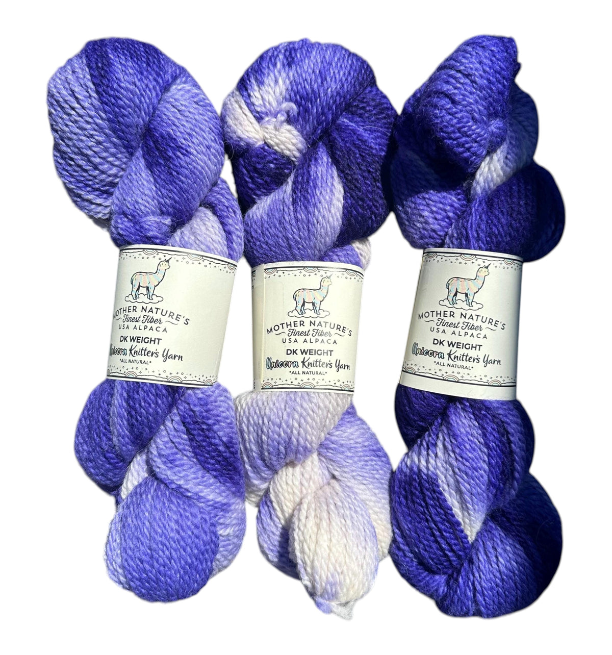 Three skeins of Oak Crest Alpacas and More variegated purple and white alpaca merino DK yarn with product labels.