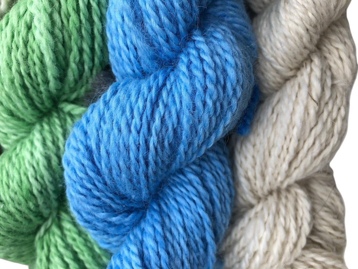 Oak Crest Alpacas and More worsted weight alpaca yarn skeins in blue, green, and natural cream for knitting projects.