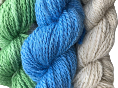 Oak Crest Alpacas and More worsted weight alpaca yarn skeins in blue, green, and natural cream for knitting projects.